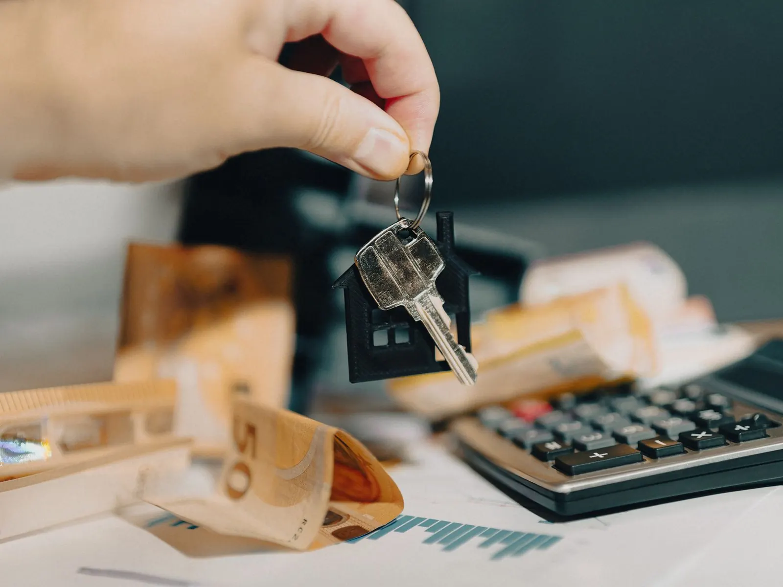 Llaves de una vivienda sobre billetes de euro y una calculadora