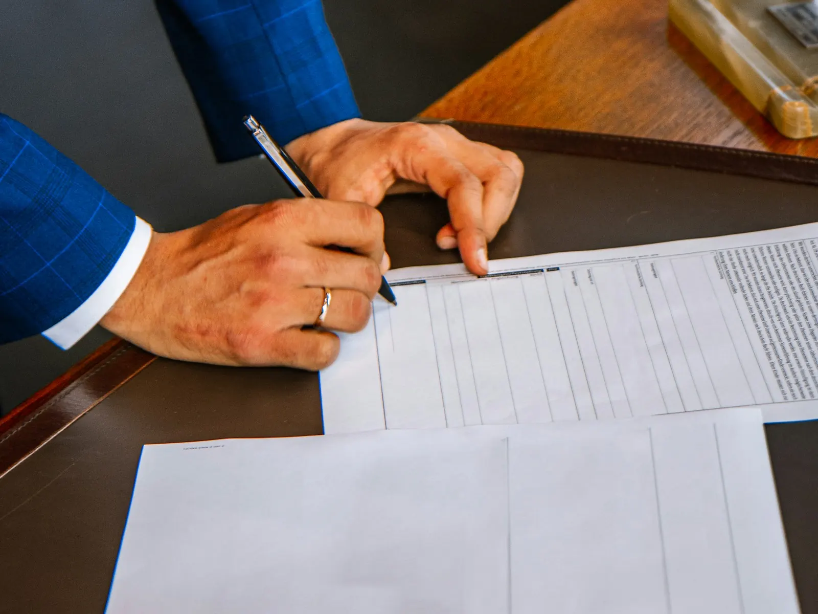 Manos rellenando un formulario impreso sobre la mesa de un despacho