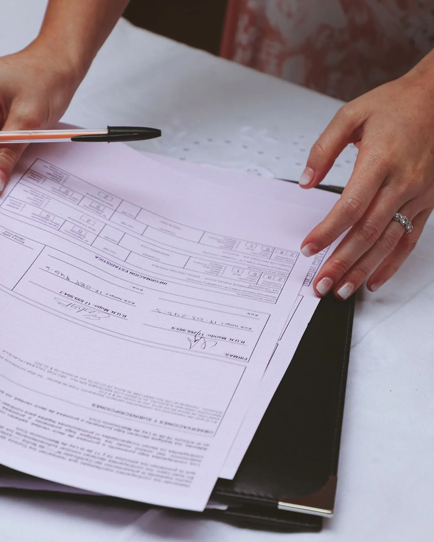 Manos revisando documentos con un bolígrafo sobre la mesa de un despacho